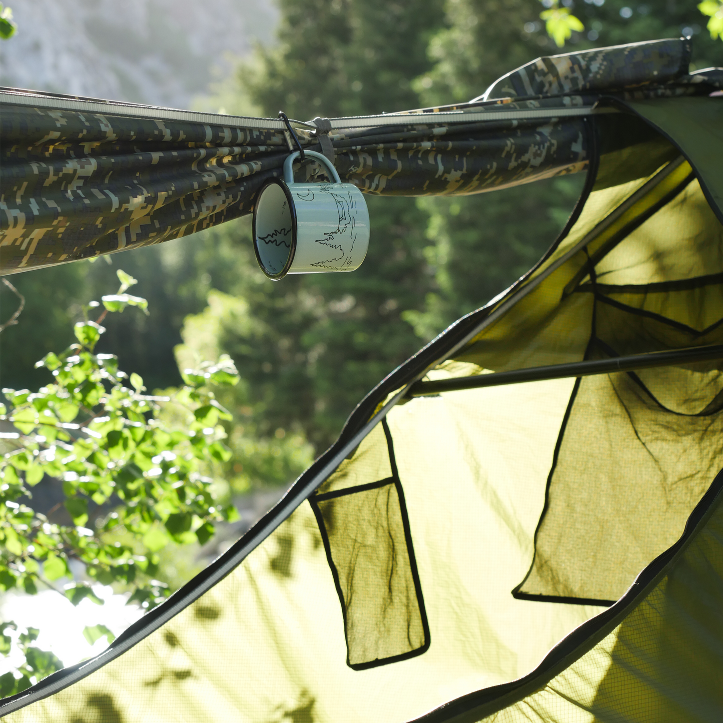 Light blue camping mug hanging by a carabiner in a lay flat hammock