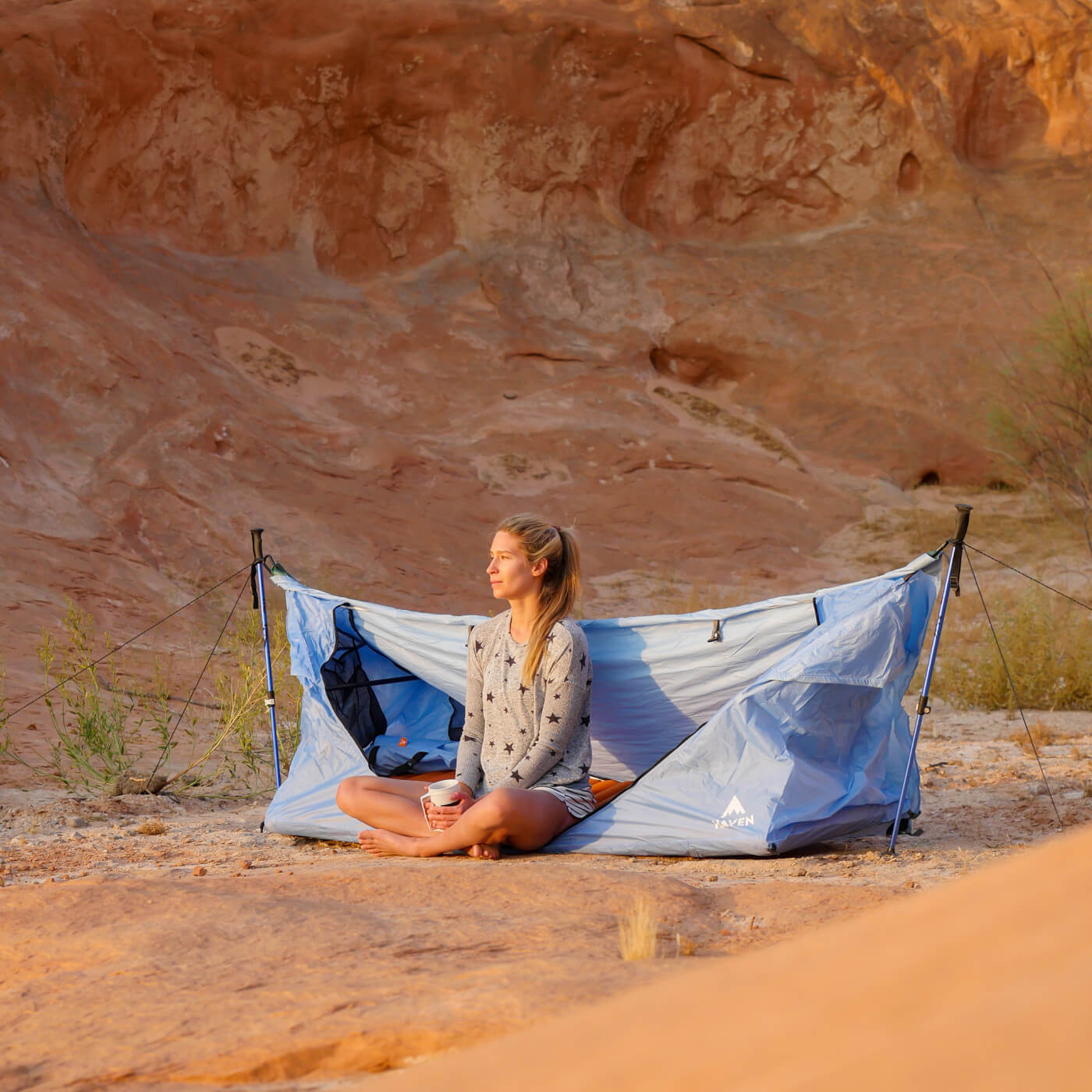 A woman sitting in a Haven Tent on the ground