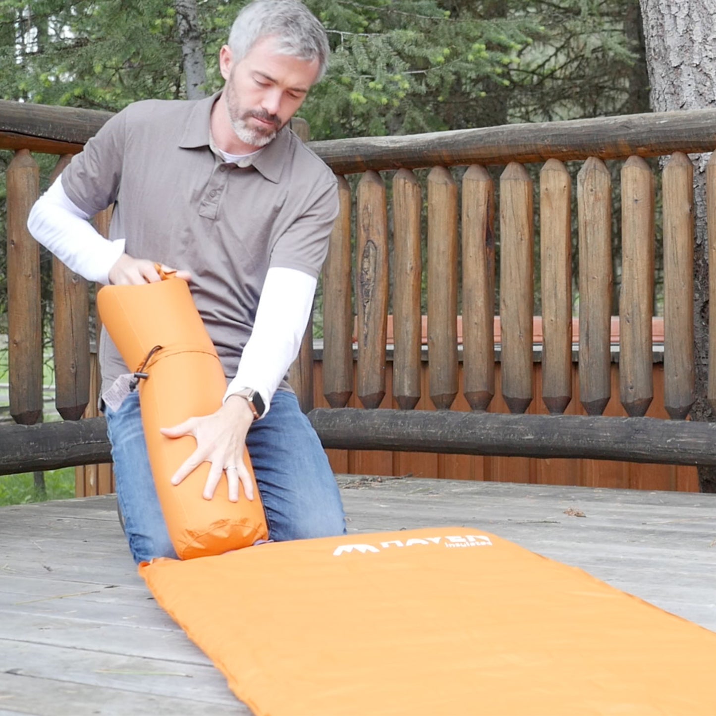 Man using a pump bag to inflate a sleeping pad