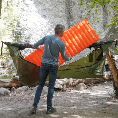 Man sets up camping hammock sleeping pad