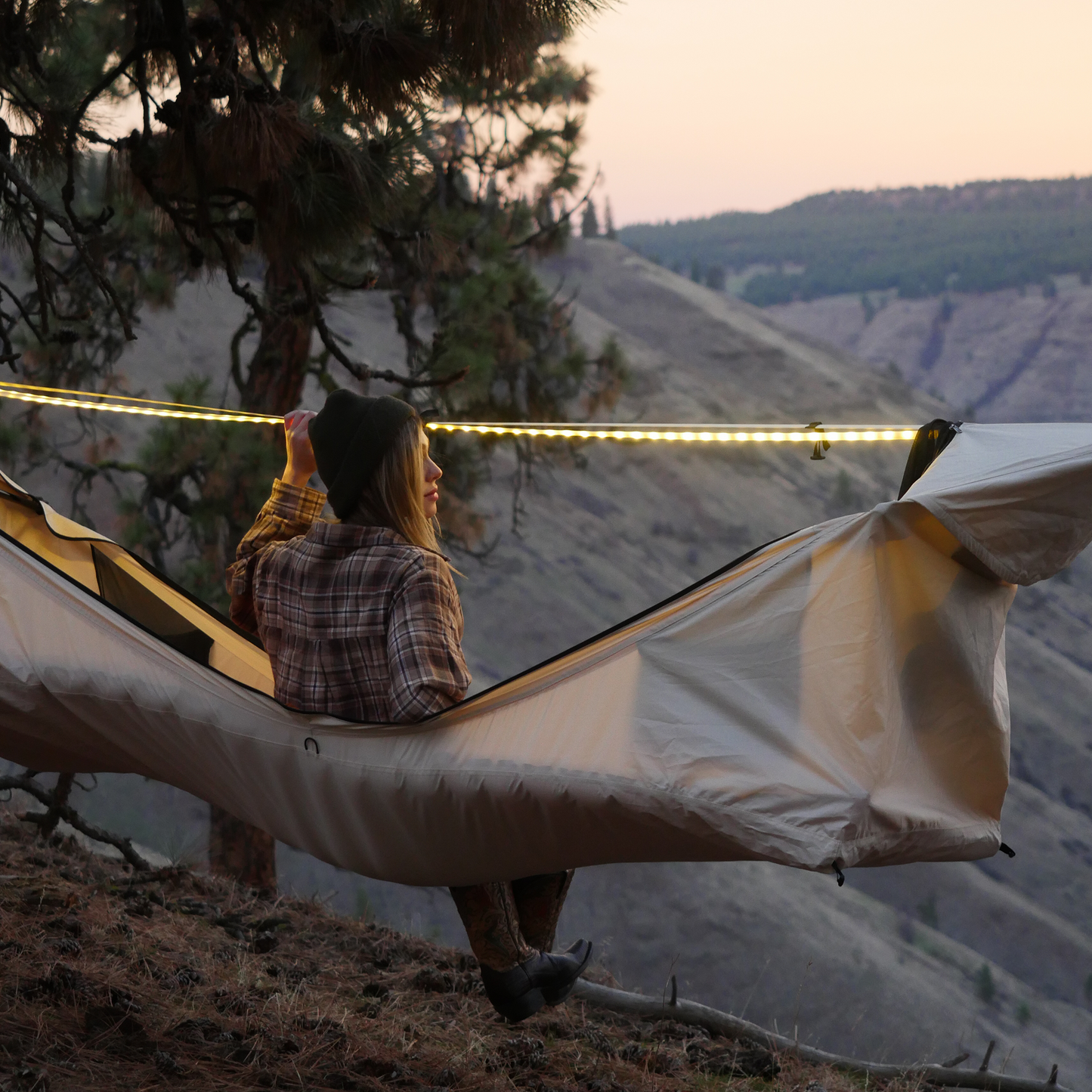 Woman sitting in a camping hammock with an LED light string