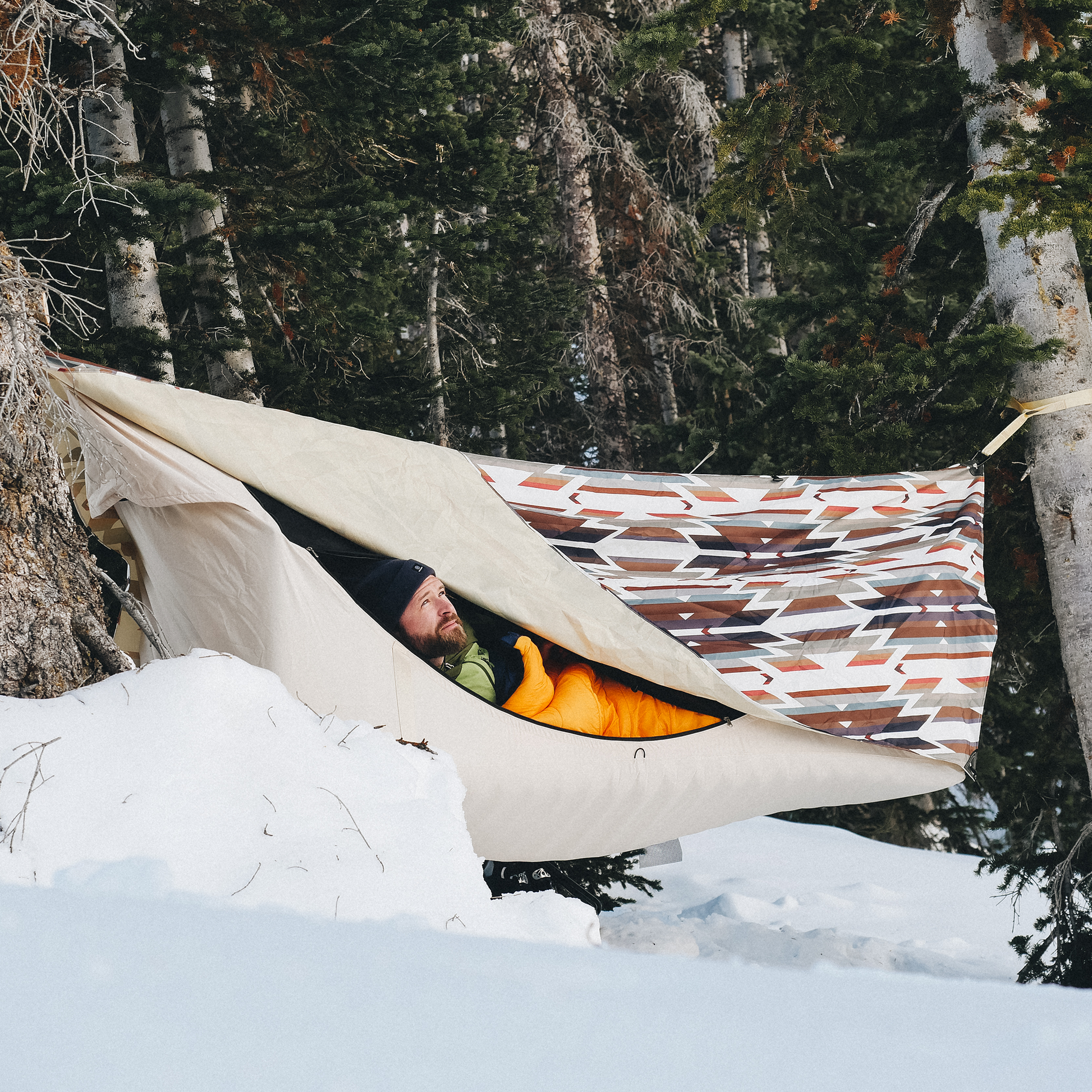 Man camping in winter in a hammock tent