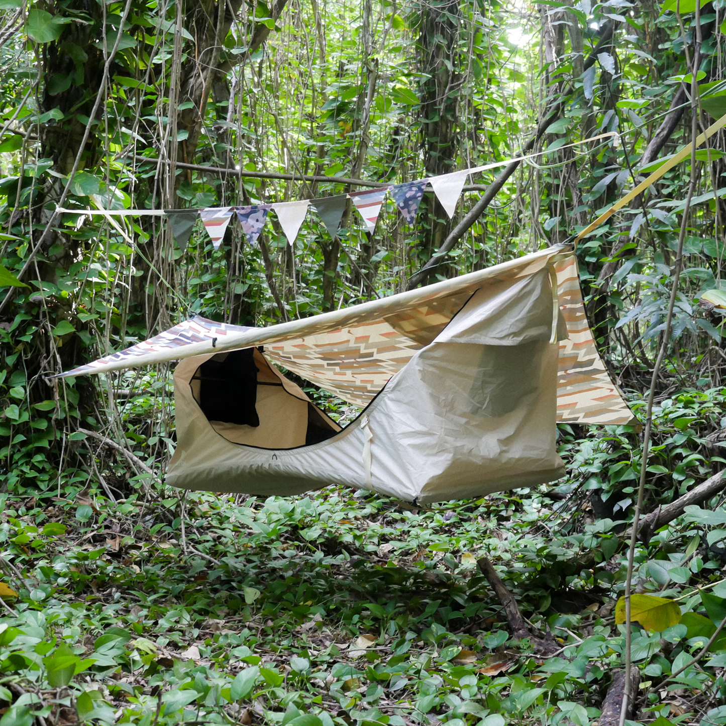 Portable camping hammock with rainfly hanging in the woods